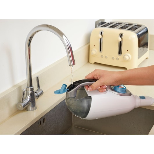 BLACKDECKER FSMH1321 steam cleaner water tank being filled at sink, close-up kitchen view.