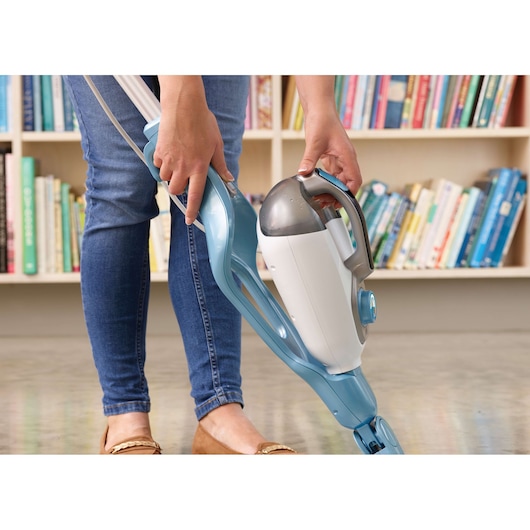BLACKDECKER FSMH1321 steam mop in blue and white, handheld part being detached, indoors near bookshelves.