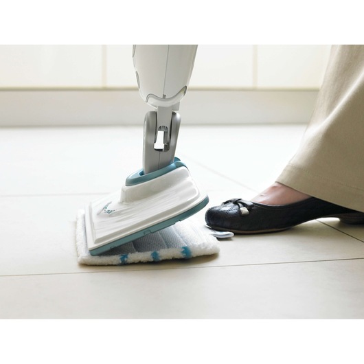 BLACKDECKER FSMP20 steam mop head with white and blue microfiber pad, foot pressing the pad on tile floor.
