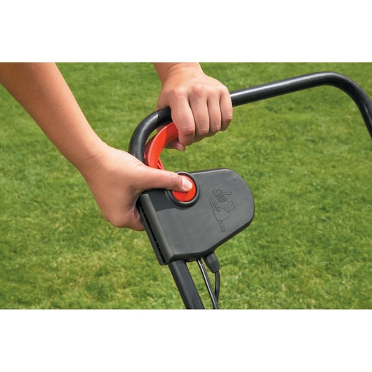 BLACKDECKER GD300 lawn rake handle close-up showing user pushing the start button on black and red control.
