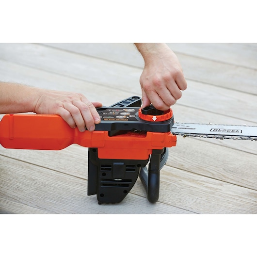 Photo of BLACKDECKER GKC1825L20 chainsaw being adjusted with hands on a wooden floor.