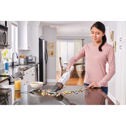 BLACK+DECKER HLVC315B11 handheld vacuum cleaning spilled cereal on kitchen counter, kitchen background.