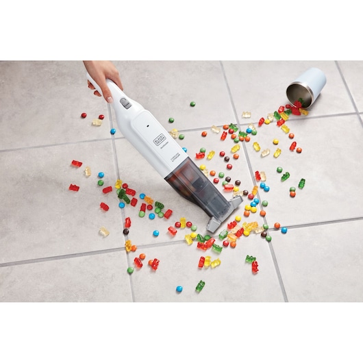 BLACKDECKER HLVC315B11 handheld vacuum cleaning spilled candy on tile floor, top view