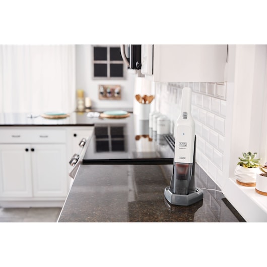 BLACKDECKER HLVC315B11 handheld vacuum in white charging on kitchen counter, side angle.