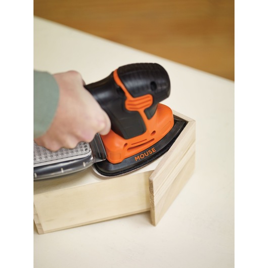 BLACKDECKER KA2000 orange and black mouse sander in use on wooden box, closeup angle