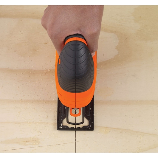 Photo of BLACKDECKER KS701PEK jigsaw cutting along a straight line on light wood, top view.