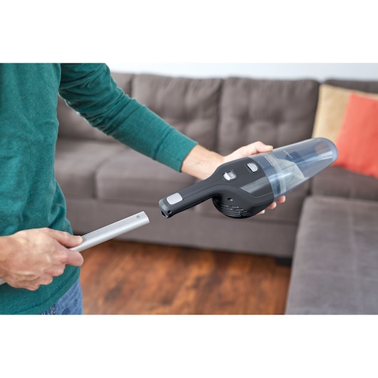BLACKDECKER NSVA315J handheld vacuum being used with a nozzle attachment near a sofa.
