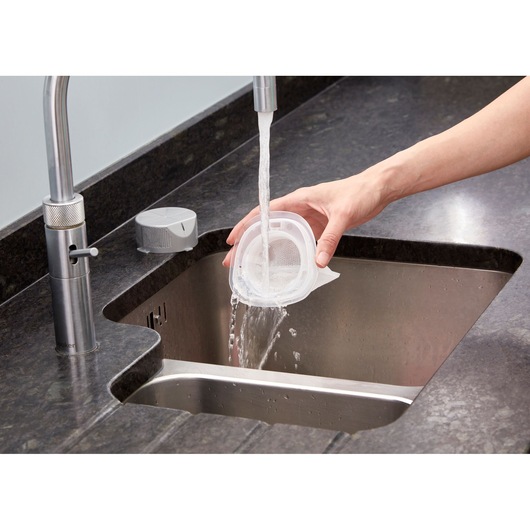 BLACKDECKER NVC215W vacuum filter being rinsed under faucet in kitchen sink, product cleaning use.