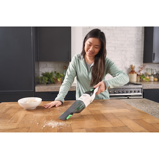 BLACKDECKER REVHV8C handheld vacuum cleaner used to clean wood kitchen counter, front angle.